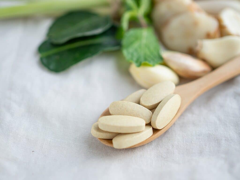 Organic medical pills with herbal plant on cloth background. Natural medicine concept